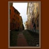 Wooden framed artistic print of some houses in the outskirts of the city. A steep alley climbs towards the skies, while a soft warm light surrounds the whole image.