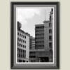 Wooden framed piece of art by Travel Photographer Scott Allen Wilson, featuring a black and white cityscape with tall blocks and linear windows.